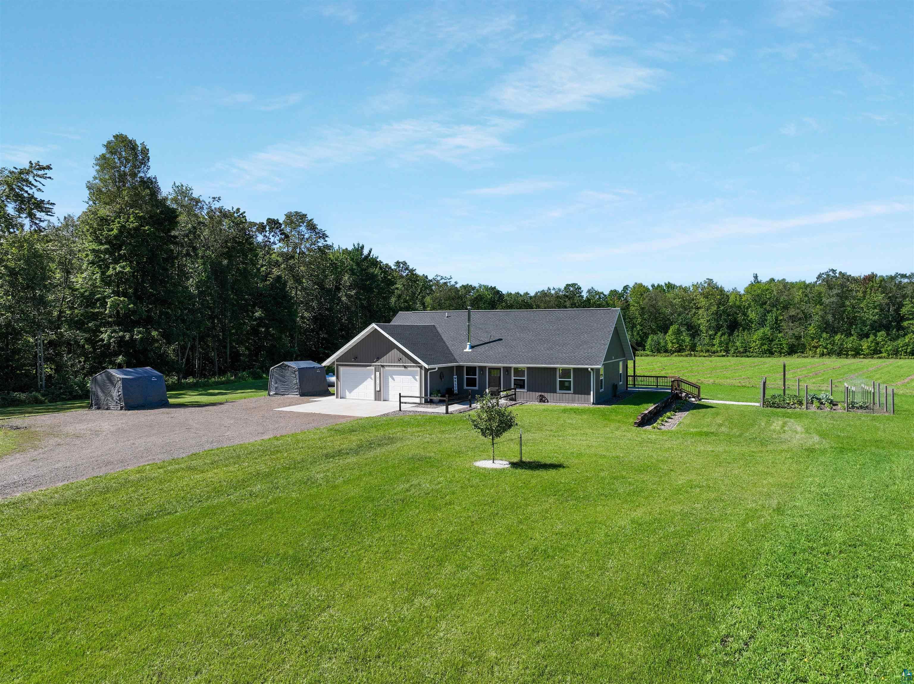 N3685 Fenander Road Spooner, WI 54801 - Photo 4 of 38 Ranch-style house featuring a garage, a front lawn, a storage unit, and a rural view