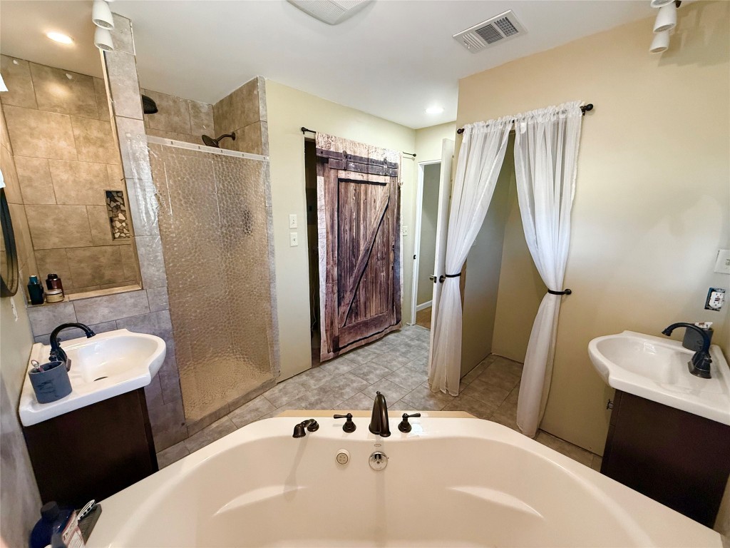 211 Rabbit Hollow Lane Georgetown, TX 78626 - Photo 16 of 32 Full bath featuring two vanities, a walk-in shower with rain feature and a jacuzzi bath