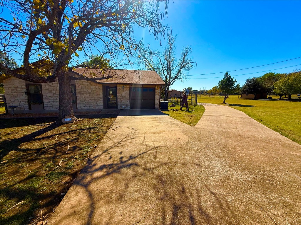 211 Rabbit Hollow Lane Georgetown, TX 78626 - Photo 2 of 32 Ranch-style house with concrete driveway, ONE ACRE, stone siding, a garage, and a front yard