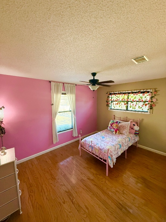 211 Rabbit Hollow Lane Georgetown, TX 78626 - Photo 24 of 32 Bedroom featuring a textured ceiling, wood finished floors, and a ceiling fan