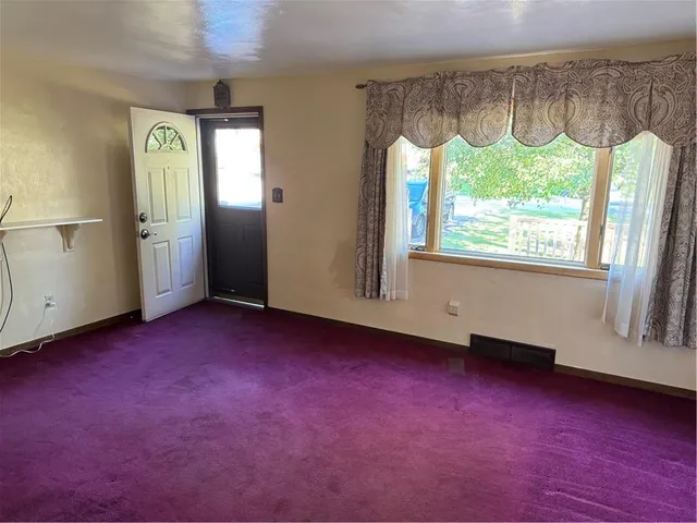 an empty room with a fireplace and a large window