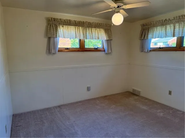 an empty room with a window and a chandelier fan