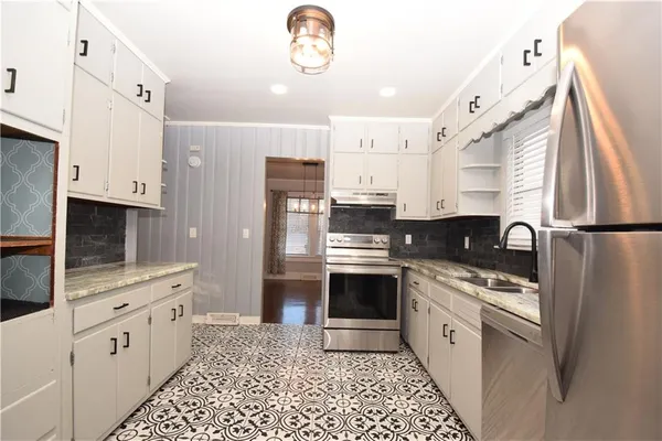 a kitchen with stainless steel appliances kitchen island granite countertop a refrigerator a stove top oven a sink and dishwasher