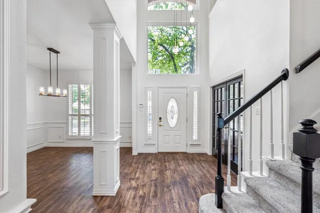 a view of an entryway with wooden floor leading to a furnished livingroom and windows