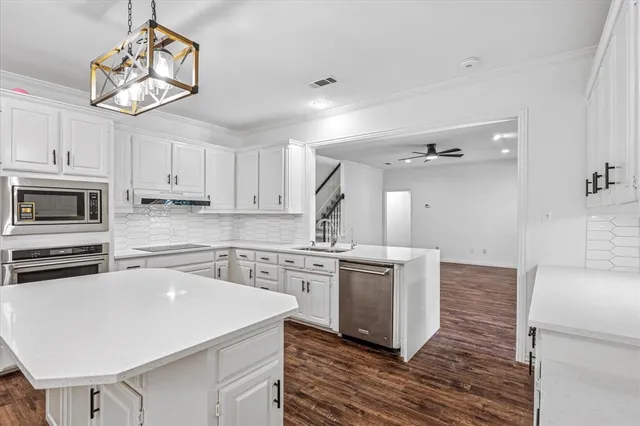 a kitchen with stainless steel appliances a stove a sink dishwasher a refrigerator and white cabinets with wooden floor