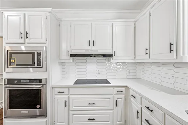 a kitchen with granite countertop white cabinets and appliances