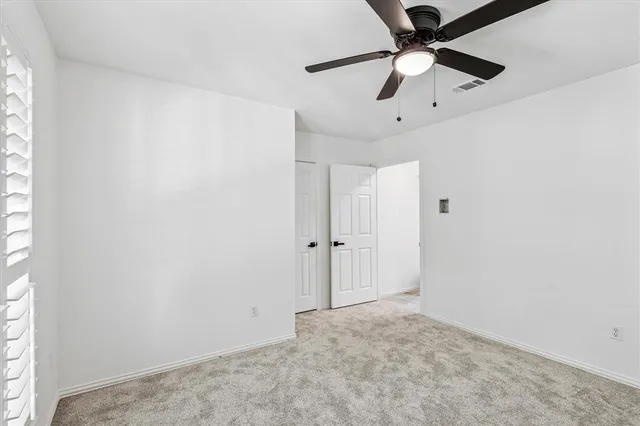 an empty room with a ceiling fan and carpet