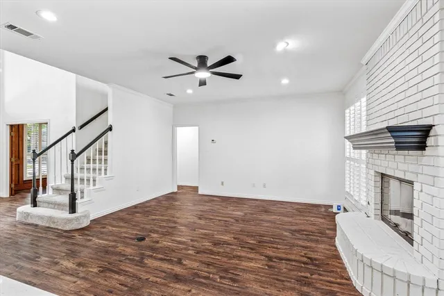 a view of empty room with fireplace and wooden floor
