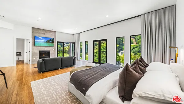 a spacious bedroom with a large bed a flat tv screen and a fireplace