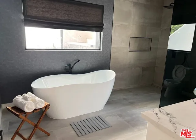 a white bath tub sitting in a bathroom next to a window