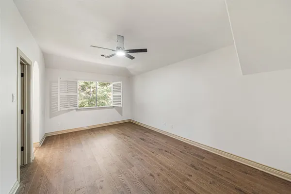 an empty room with wooden floor chandelier fan and windows