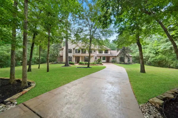 a view of a house with a big yard and large trees