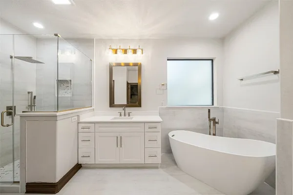 a spacious bathroom with a tub sink shower and mirror