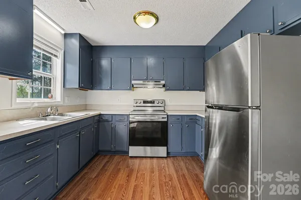 a kitchen with granite countertop a refrigerator stove and sink