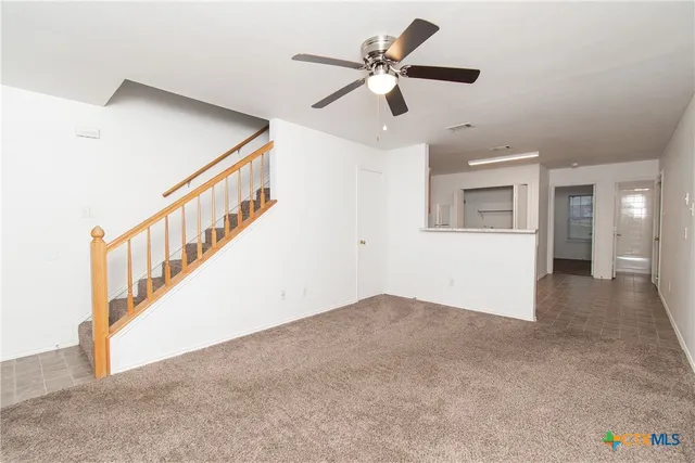 an empty room with ceiling fan and windows