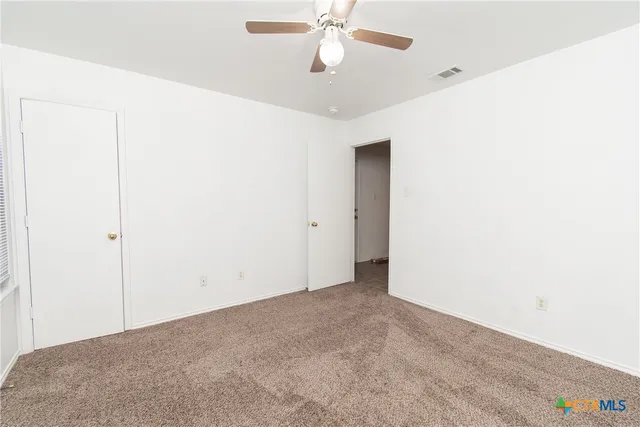 an empty room with a ceiling fan and carpet