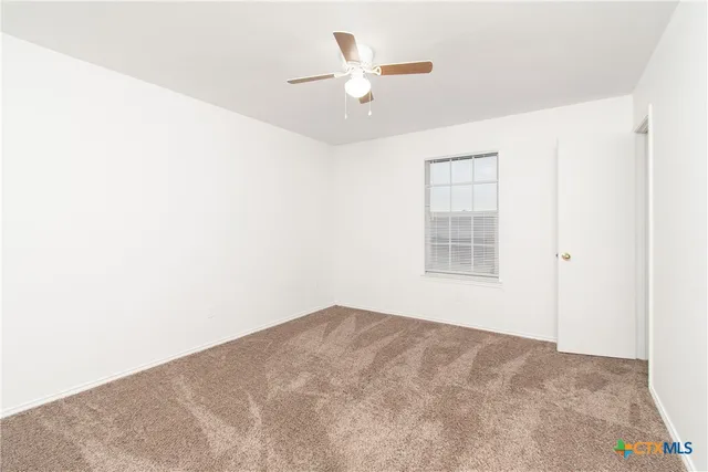 an empty room with a ceiling fan and a window