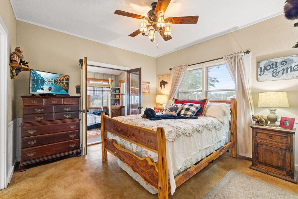 257 Encino Loop Kerrville, TX 78028 - Photo 32 of 92 a bedroom with a bed and a chandelier