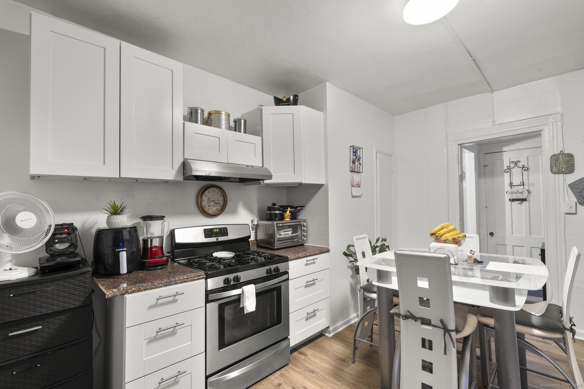 865 Iranistan Avenue Bridgeport, CT 06605 - Photo 14 of 35 a kitchen with stainless steel appliances granite countertop a stove a sink dishwasher and white cabinets with wooden floor