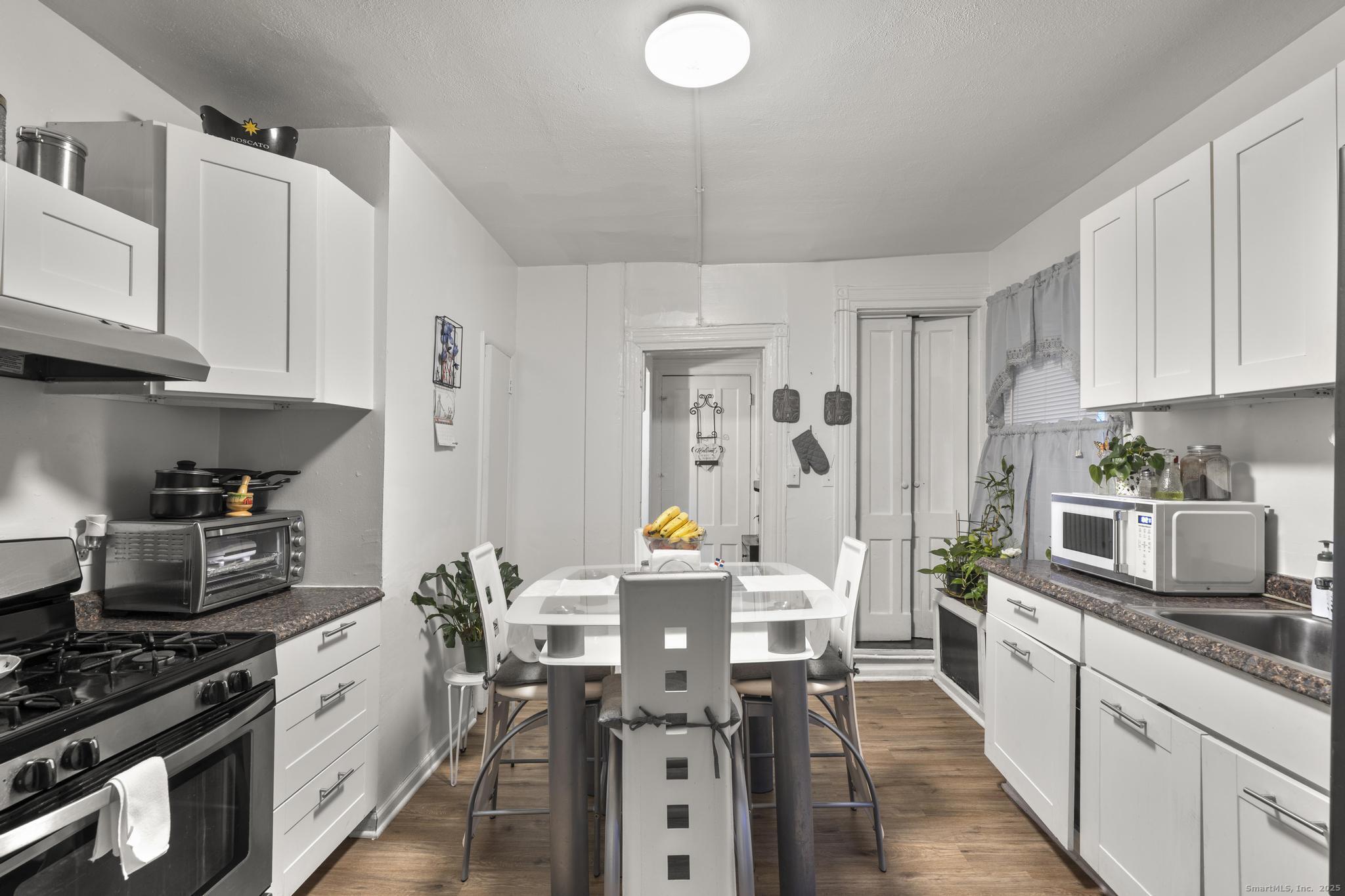 865 Iranistan Avenue Bridgeport, CT 06605 - Photo 15 of 35 a kitchen with stainless steel appliances a stove a sink dishwasher and cabinets with wooden floor