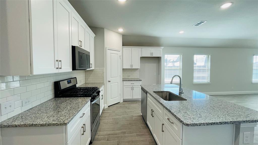 2131 Erika Lane Forney, TX 75126 - Photo 6 of 20 a kitchen with granite countertop a sink and a stove top oven with wooden floor
