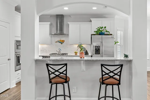a kitchen with stainless steel appliances a table and chairs in it