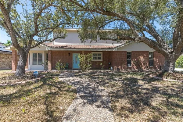 a view of a house with a yard and large tree
