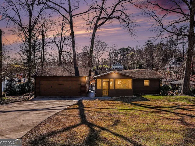 a front view of a house with a yard and large tree