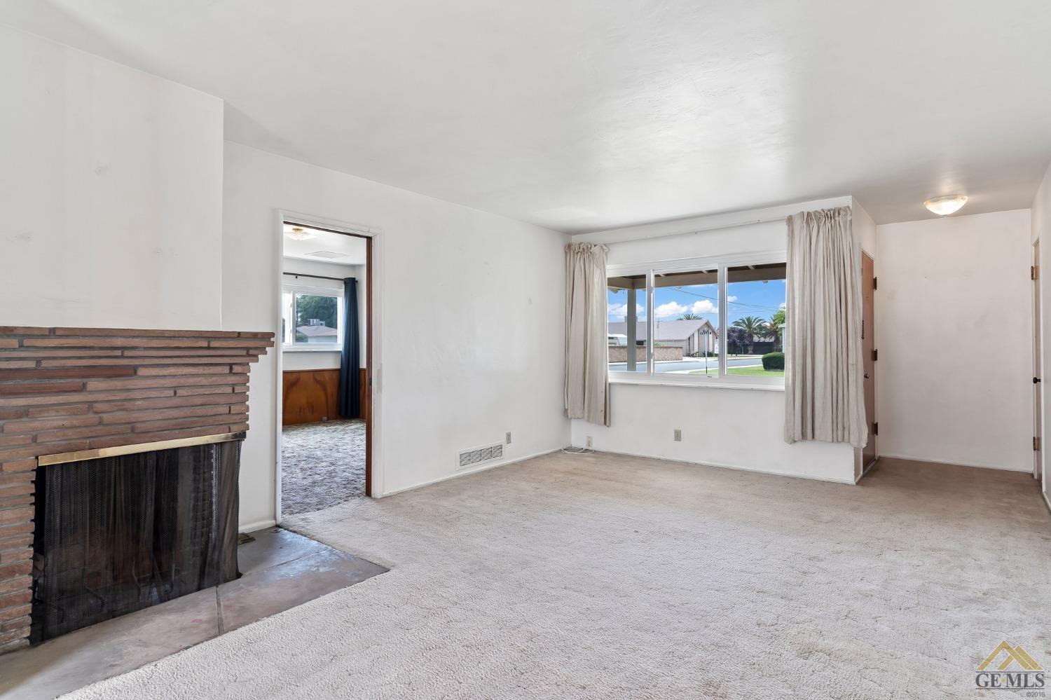 Undisclosed Address Wasco, CA 93280 - Photo 9 of 30 an empty room with a fireplace and wooden floor