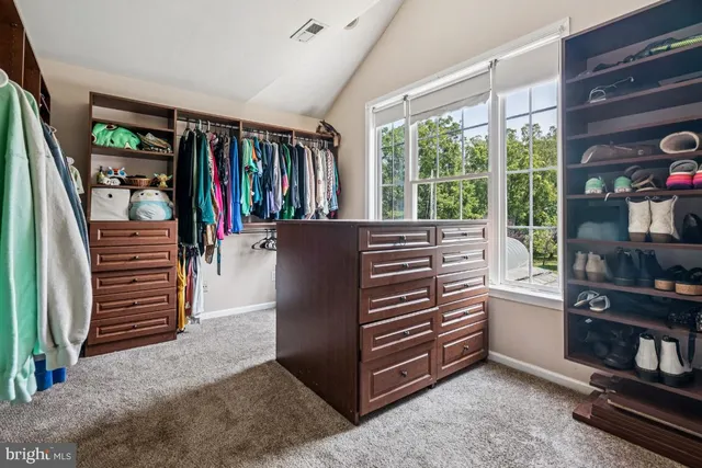 a view of walk in closet with clothes and shoes