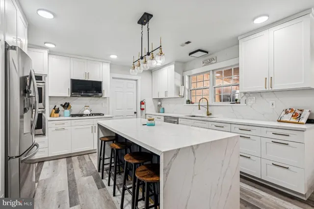 a kitchen with a sink a center island cabinets and stainless steel appliances