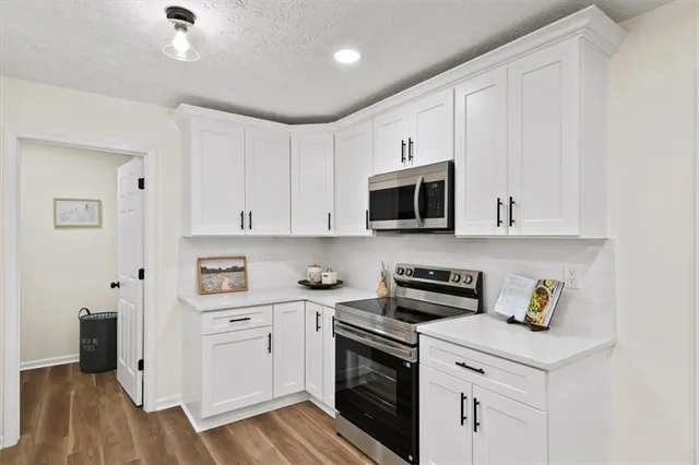 a kitchen with stainless steel appliances granite countertop white cabinets and a stove