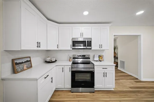 a kitchen with granite countertop white cabinets and stainless steel appliances