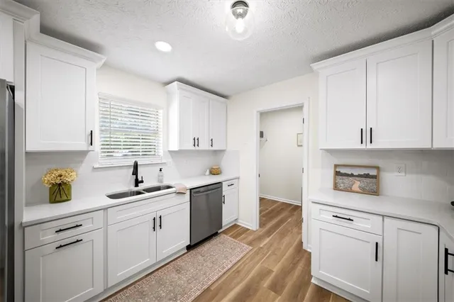a kitchen with a sink dishwasher stove and white cabinets