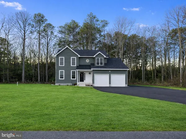 a front view of a house with a yard and trees