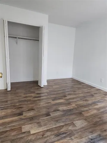 a view of an empty room with wooden floor and closet
