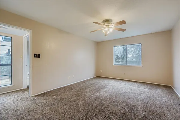 an empty room with windows and fan