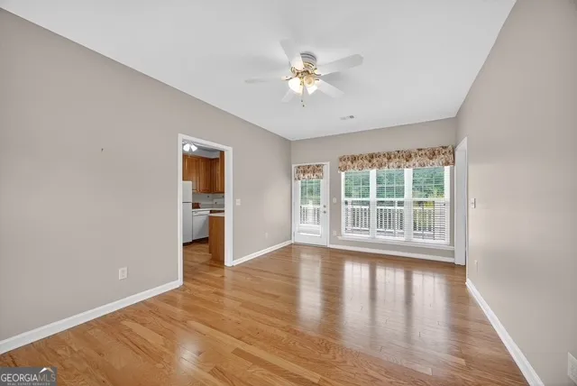 a view of an empty room with wooden floor and a window