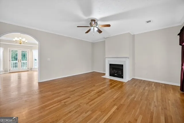 an empty room with wooden floor fireplace and windows