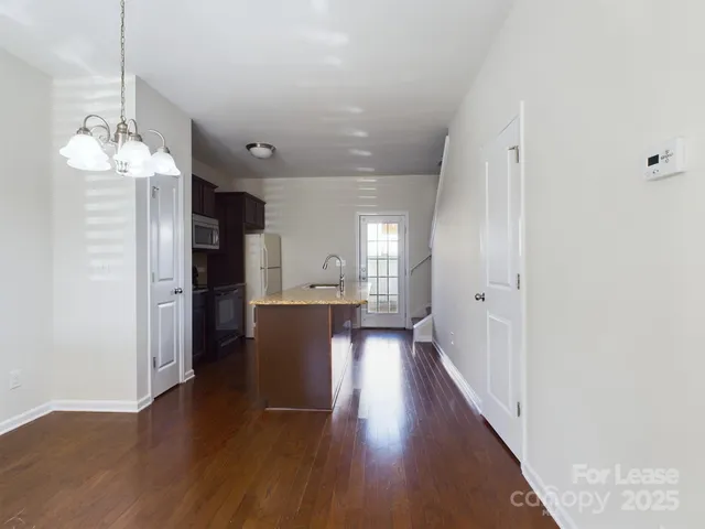 a view of a hallway with wooden floor and a kitchen