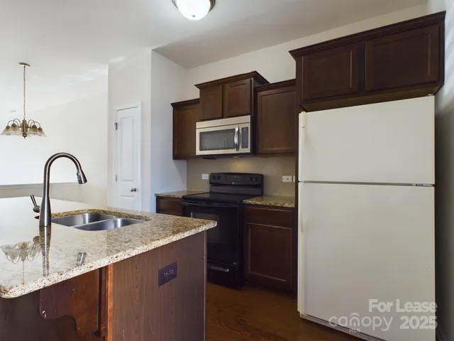 a kitchen with granite countertop a refrigerator and a stove top oven