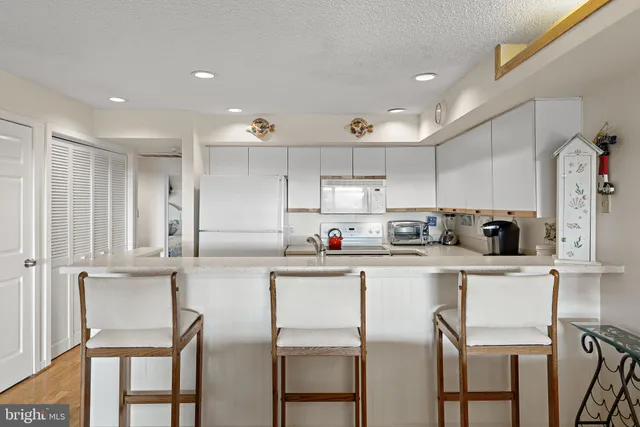 a kitchen with white cabinets and chairs
