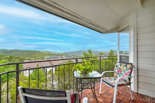 a view of a city from a balcony with dining table and chairs