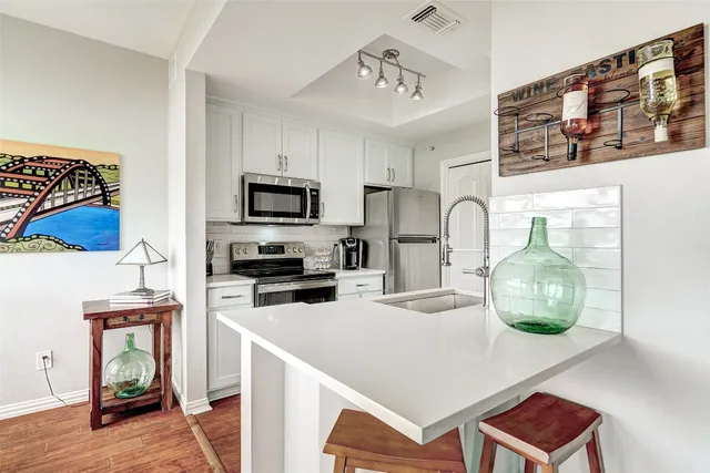 a kitchen with stainless steel appliances a stove a sink a microwave a refrigerator and cabinets