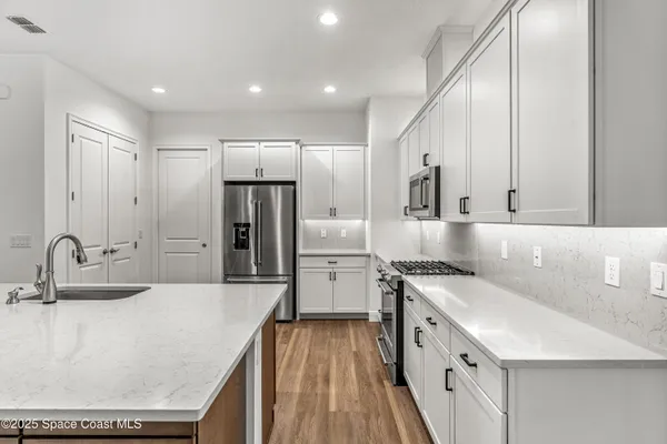 a kitchen with a sink a counter top space stainless steel appliances and cabinets