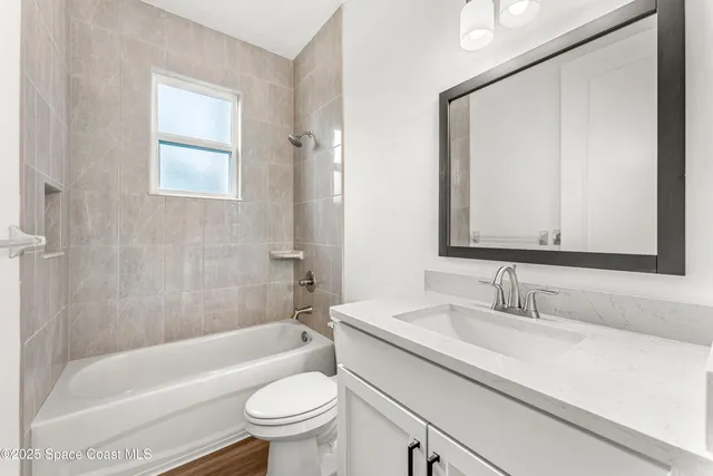 a bathroom with a sink a toilet a mirror a bathtub and shower