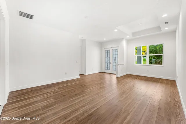 an empty room with wooden floor and windows
