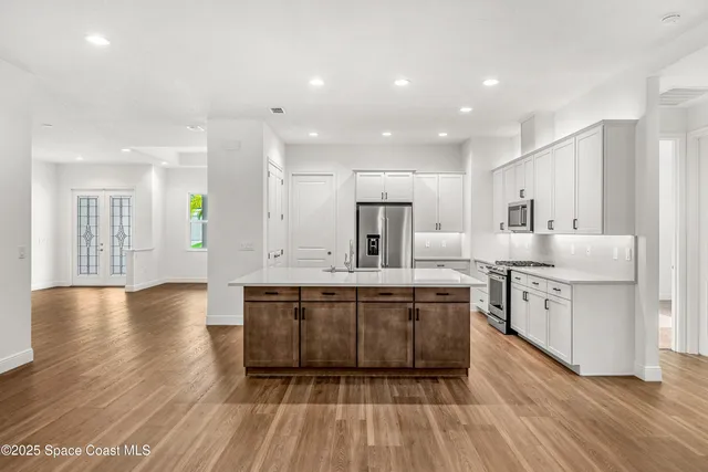a large kitchen with stainless steel appliances a large counter top a stove and a wooden floors