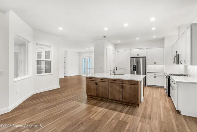a large kitchen with kitchen island wooden floors and stainless steel appliances