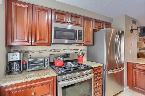 a kitchen with stainless steel appliances granite countertop a stove refrigerator and cabinets